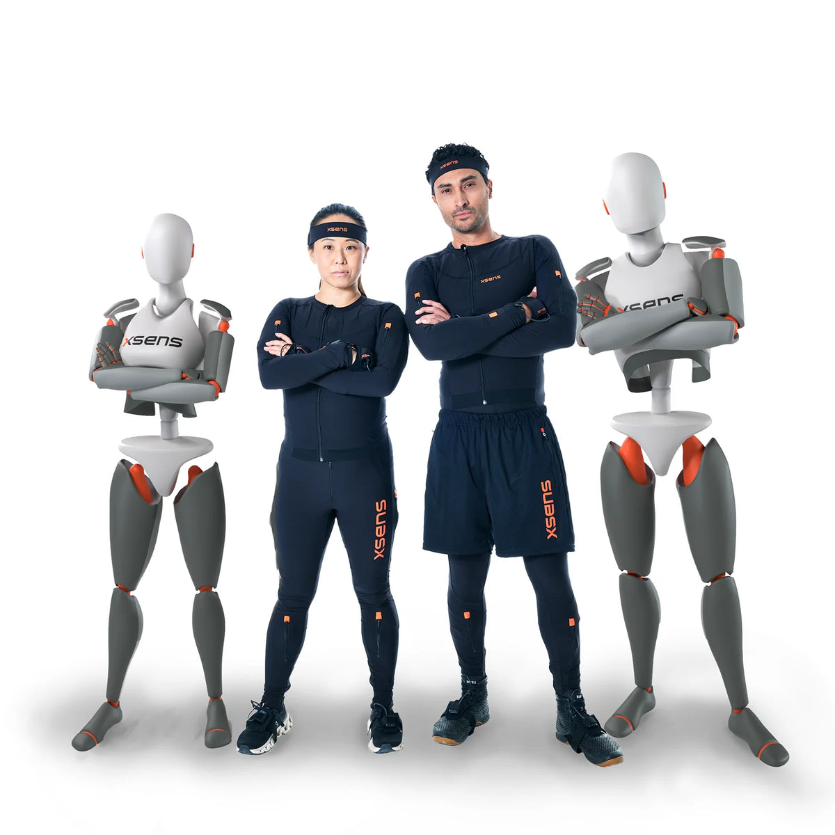 Two people wearing dark blue athletic suits with 'Xsens' branding, standing between two mannequins also wearing 'Xsens' suits.