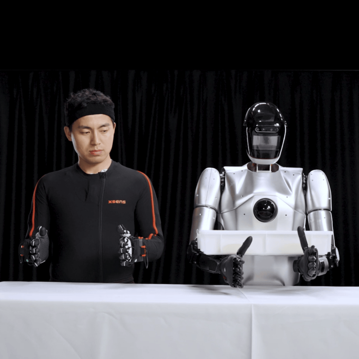 Xsens-suited operator beside a humanoid robot in an Xsens robotics demonstration